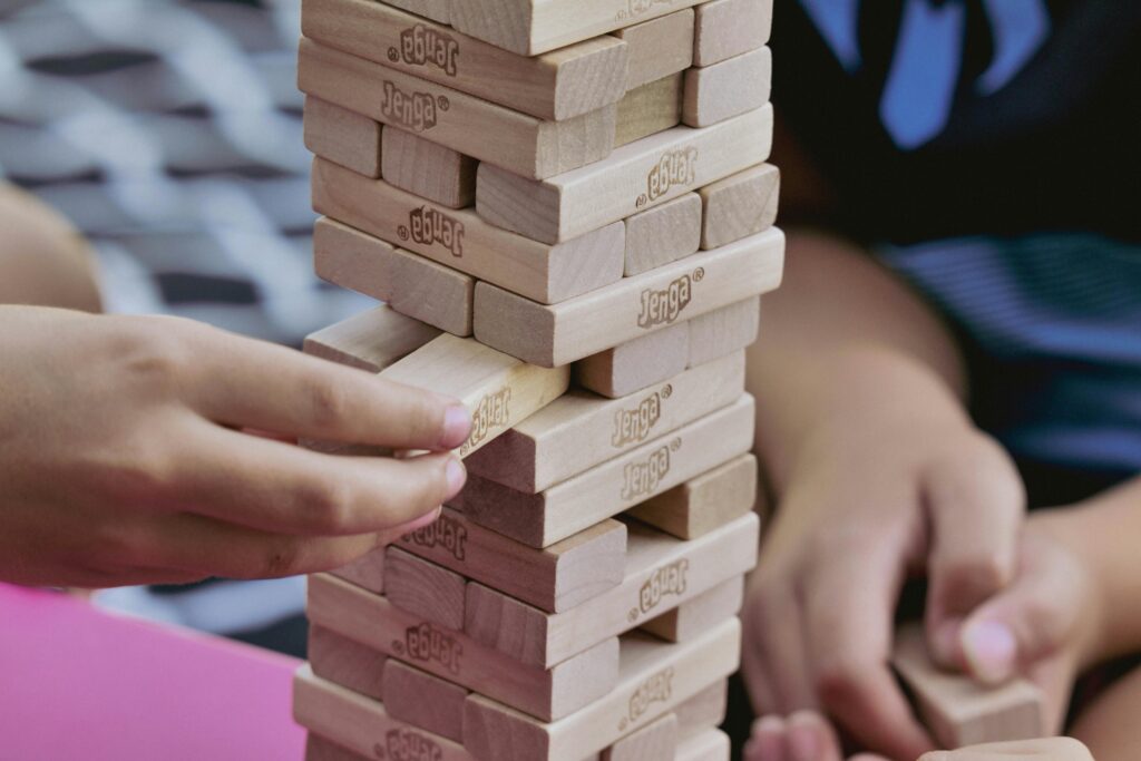 Close-up of children playing Jenga indoors, focusing on the tension and excitement of the game.